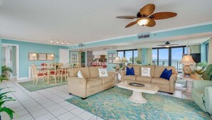 A spacious living room with two sofas, a coffee table, and a dining area with chairs and a table. - Watercrest 203 - FREE Beach Chairs! (Panama City Beach)