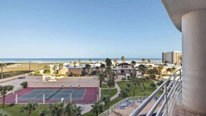 A tennis court, pool area, and beach view from a balcony. - South Padre Resort Rentals - Sunchase IV #327 (South Padre Island)