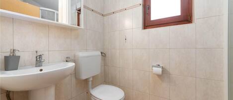A bathroom with a white sink, toilet, and a window above the toilet.