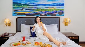 Habitación de hotel con cama, bufé de desayuno y un cuadro de barcos en la pared.