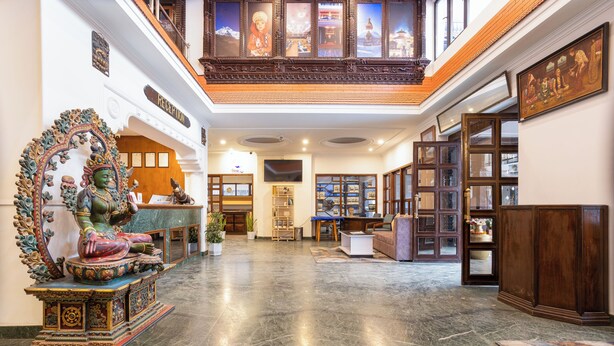Un vestíbulo amplio con una recepción, una estatua de Buda y un aparador de madera tradicional.
