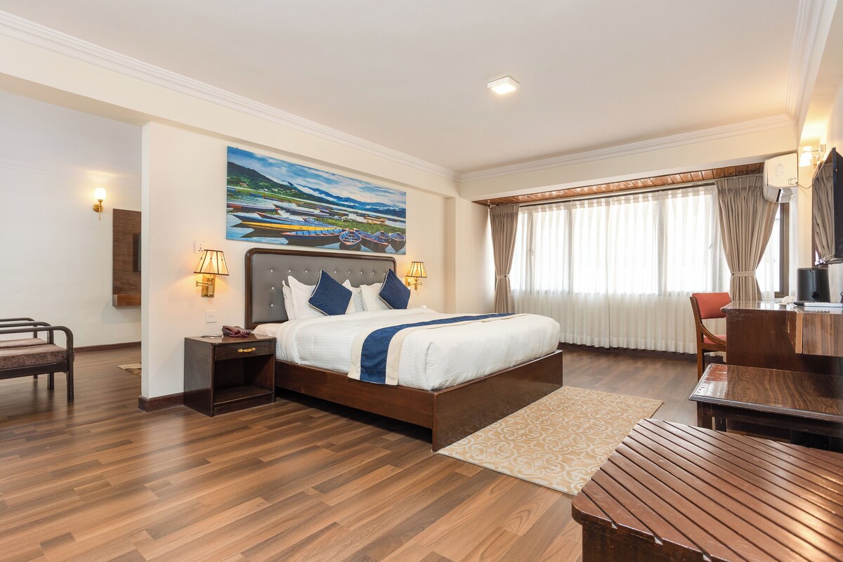 Una habitación de hotel con una cama grande, suelo de madera, un escritorio y una silla.