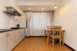Uma cozinha com fogão, pia e um espaço de refeições com mesa e cadeira.