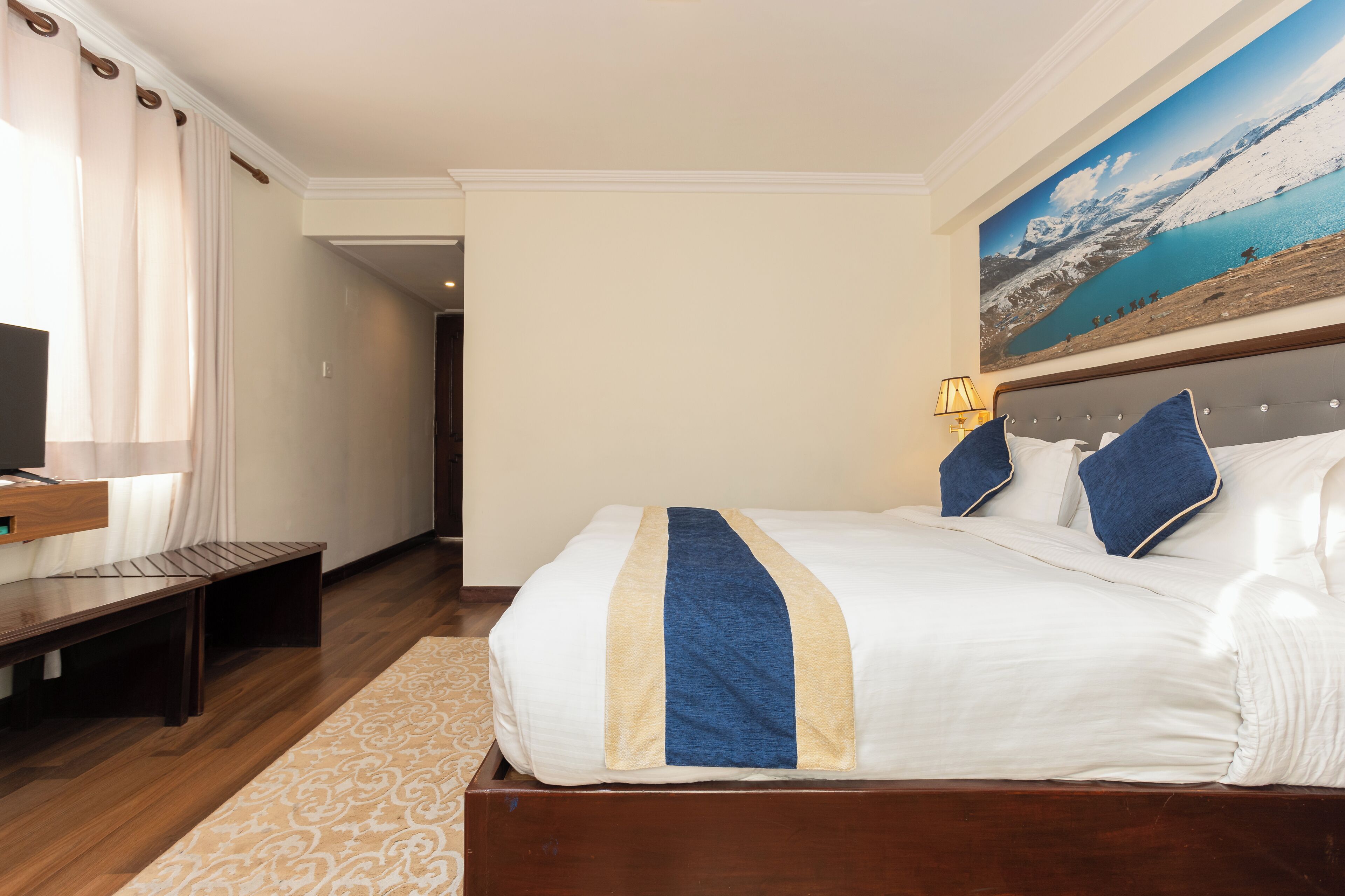 A hotel room with a bed, a desk, and a television.
