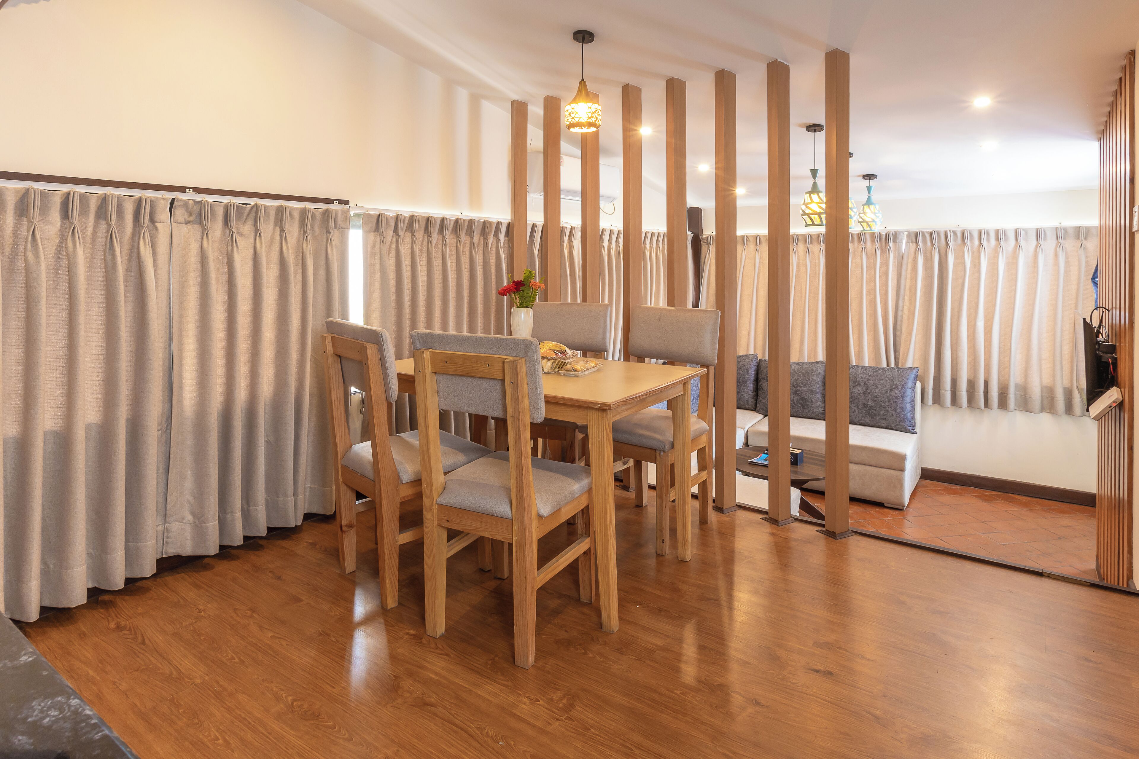 A dining area with a wooden table and chairs, a sofa, and a decorative vase.