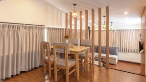 A dining area with a wooden table and chairs, a sofa, and a decorative vase. - Kathmandu Business Hotel (Kathmandu)