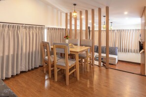 A dining area with a wooden table and chairs, a sofa, and a decorative vase. - Kathmandu Business Hotel (Kathmandu)