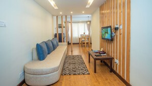 A modern living room with a sofa, a coffee table, and a TV mounted on the wall. - Kathmandu Business Hotel (Kathmandu)