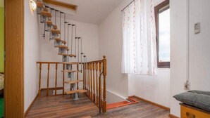 Un escalier avec des rampes en bois et des supports métalliques, un banc en bois et une fenêtre avec des rideaux.