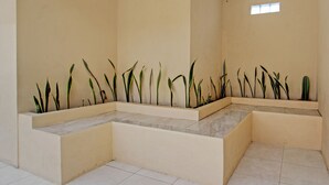Una habitación con piso de baldosas, un muro bajo color beige y una ventana.