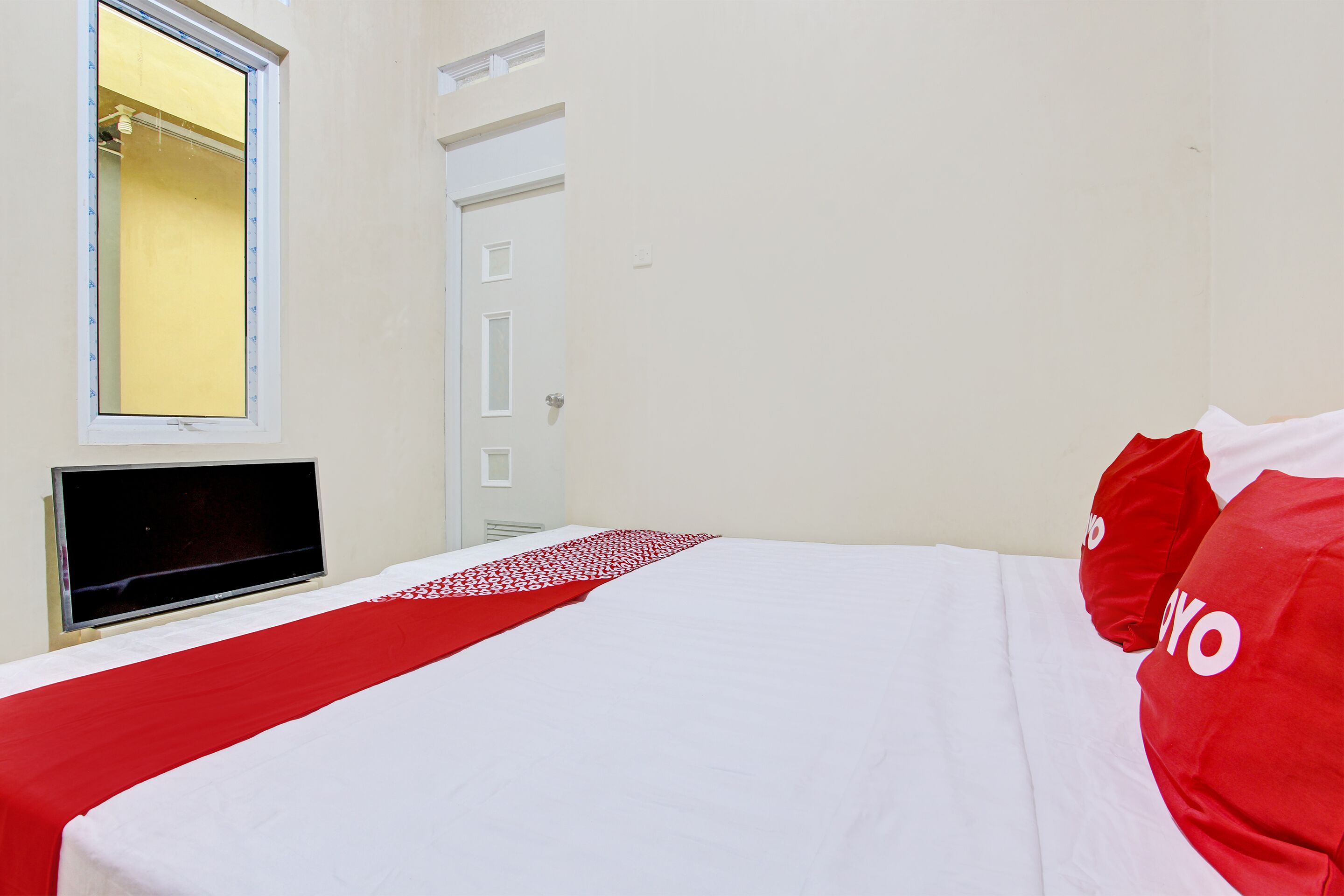 Una habitación de hotel con una cama, un televisor y una puerta.