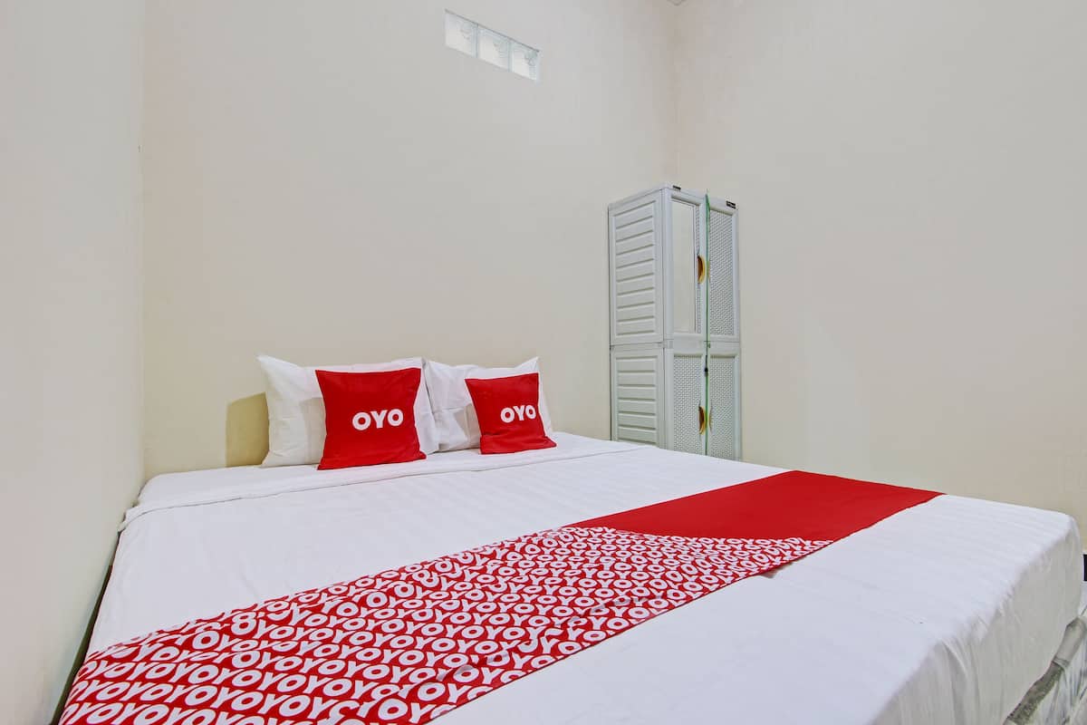 Ein Hotelzimmer mit einem Bett, weißen Wänden und einer Bettdecke mit roten und weißen Mustern.