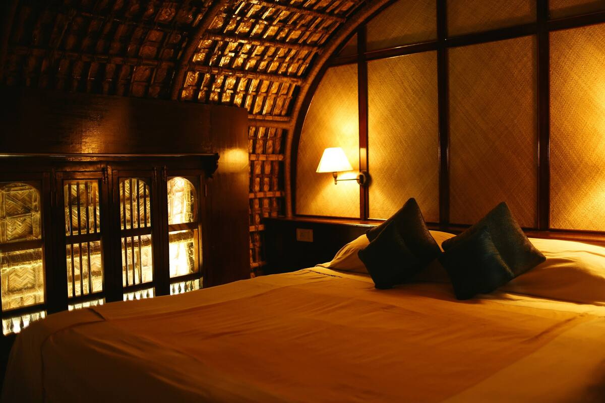 Een kamer met een bed, een lamp en een raam met uitzicht op een bakstenen muur.