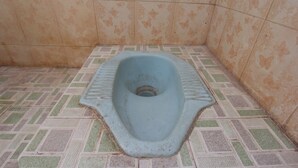 Un WC a pavimento dal design essenziale, circondato da piastrelle decorate.