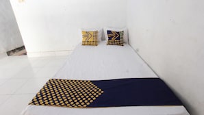 Un letto singolo con un materasso bianco e due cuscini a motivi geometrici.