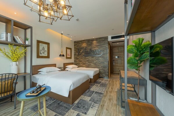 Una habitación de hotel moderna con una cama grande, una mesita con un hervidor de agua, una estantería y una pared con un cartel que dice 'Vintage'.
