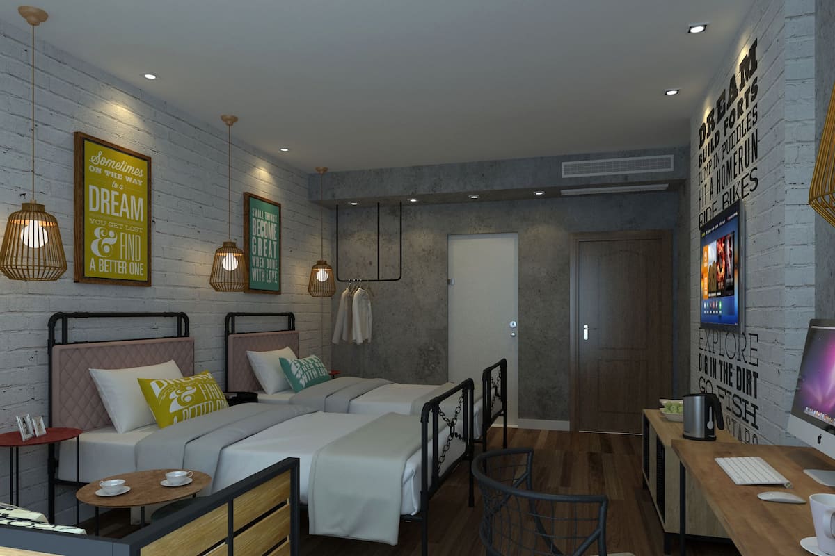A modern bedroom with two beds, a desk, and a TV.