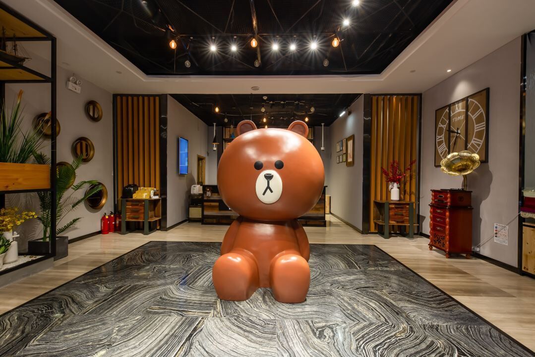 A modern interior with a large bear sculpture in the center, wooden paneling, and a clock on the wall.