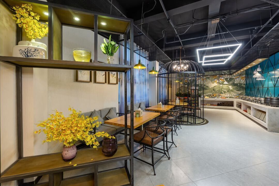 A modern restaurant with wooden tables and chairs, a bar area, and decorative plants.