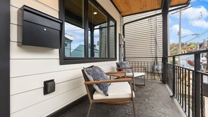A covered porch with two rocking chairs and a mounted TV. - ★ HostWise Stays ★ Off-Street Parking, 2 Full Baths, Great Patio! (Pittsburgh)