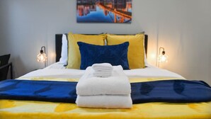 A neatly made bed with a blue and yellow bedspread, two pillows in blue and yellow, and a folded white towel on the bed. - ★ HostWise Stays ★ Off-Street Parking, 2 Full Baths, Great Patio! (Pittsburgh)
