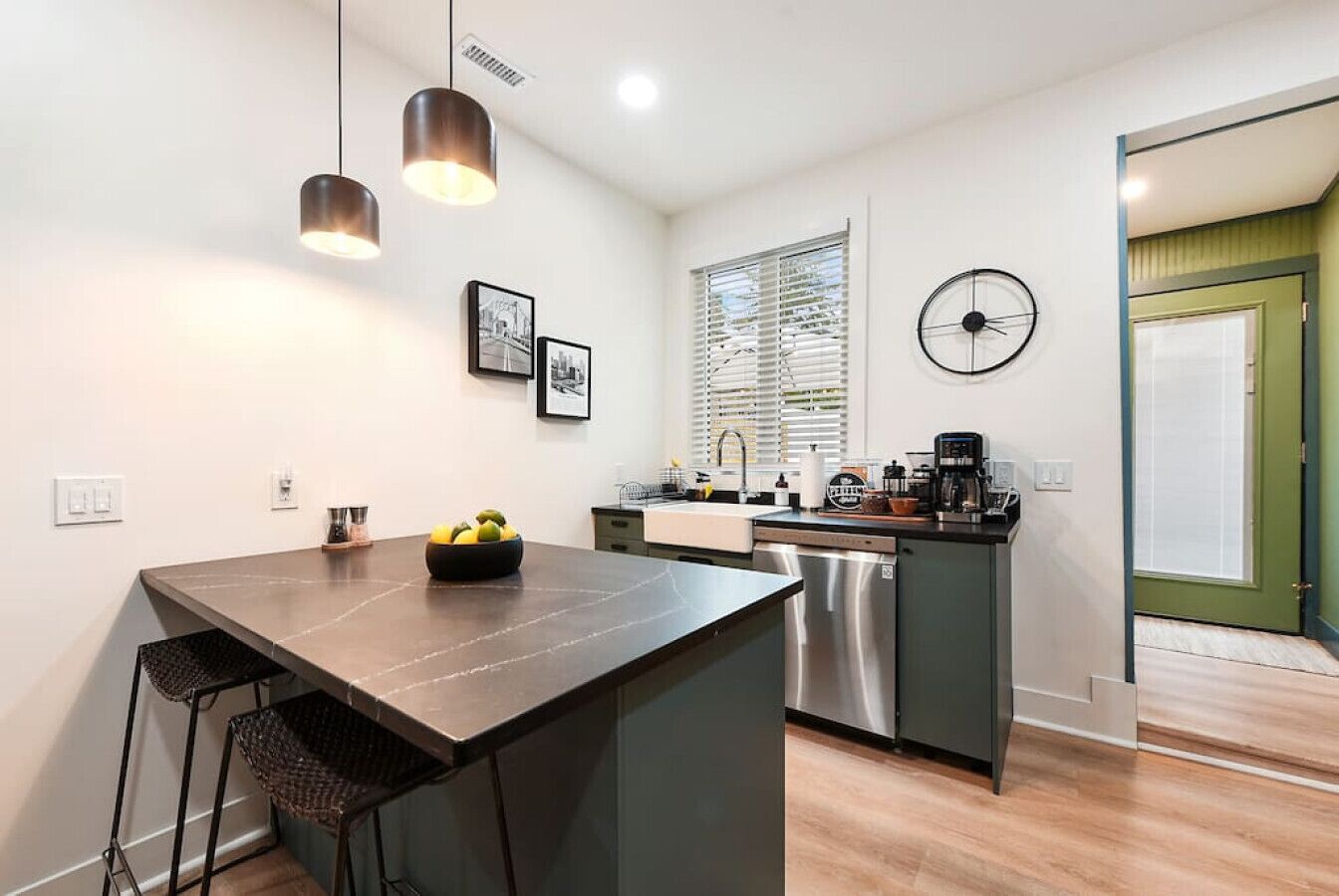 A modern kitchen with a central island, stainless steel appliances, and a dining area with bar stools.