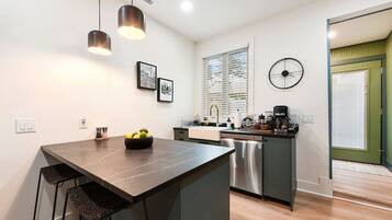 A modern kitchen with a central island, stainless steel appliances, and a dining area with bar stools.