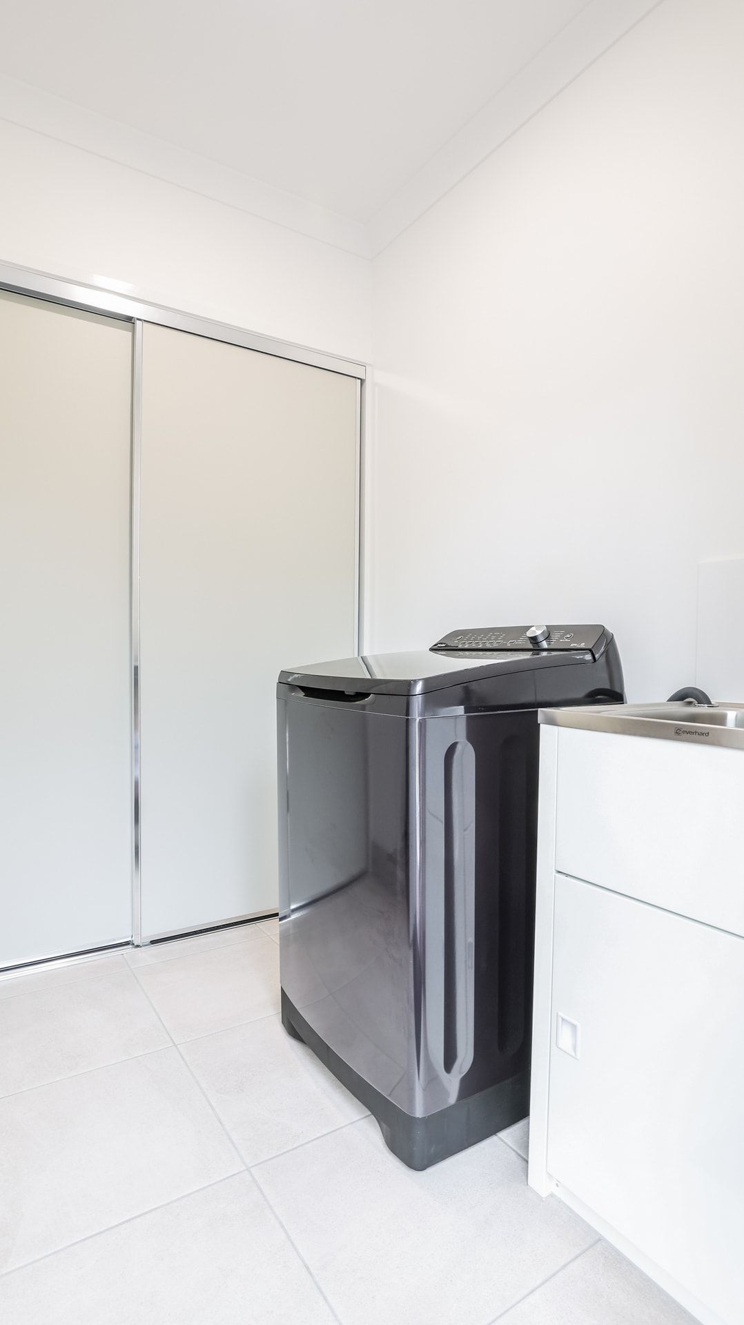 A compact laundry room with a washing machine, a dryer, and a small cabinet.