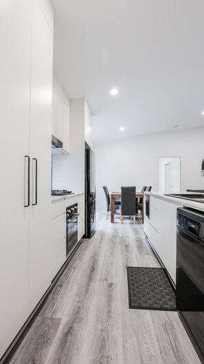 Una cucina moderna con mobili bianchi, un'isola centrale e una zona pranzo con sedie.
