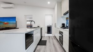 Una cucina moderna con un'isola grande, elettrodomestici integrati e vista su una barca sullo schermo televisivo.