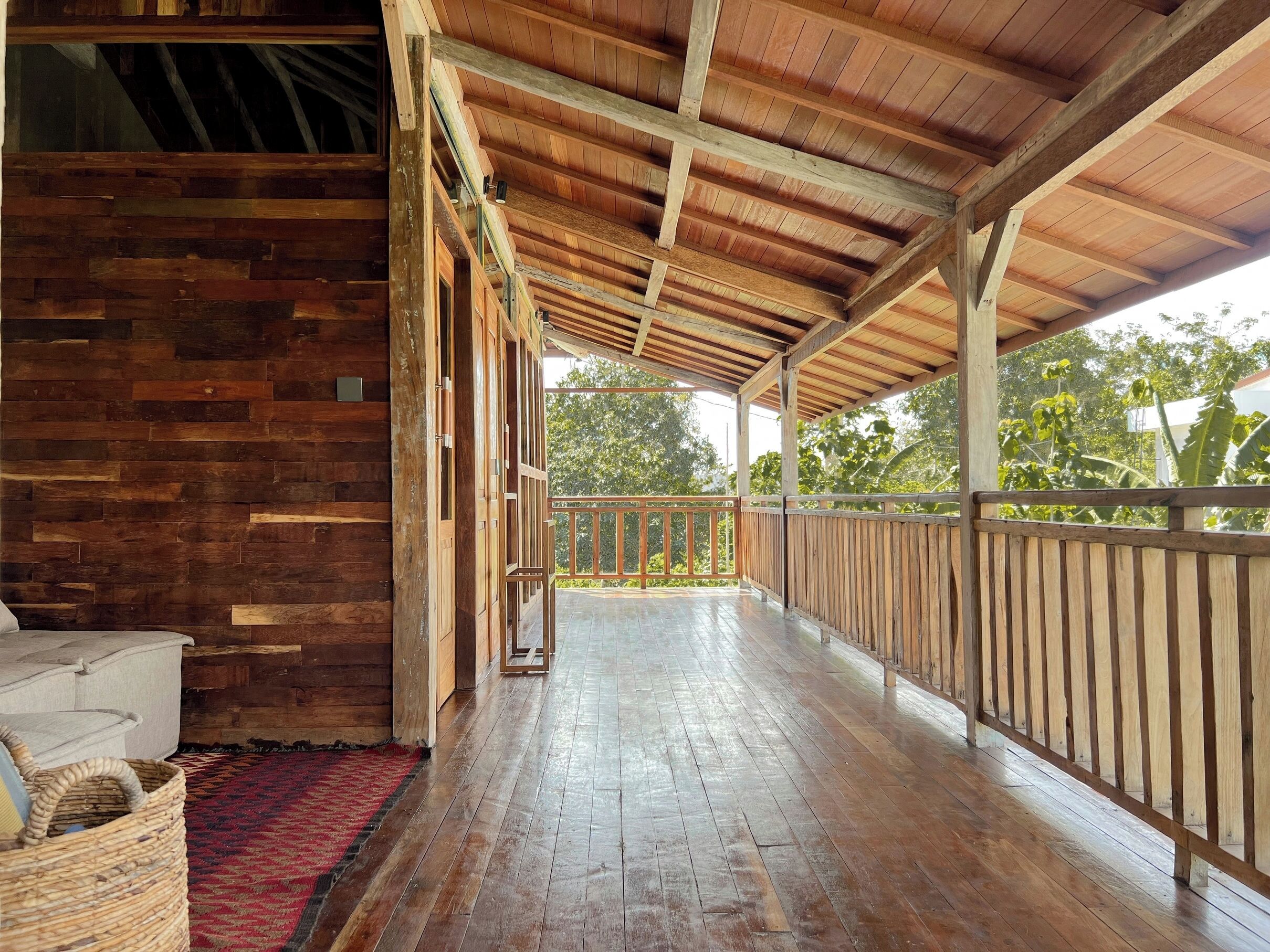 A covered wooden porch with a view of greenery outside.