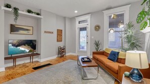 A living room with a TV, sofa, coffee table, and plants.
