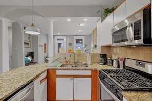 A modern kitchen with granite countertops, stainless steel appliances, and a central island.