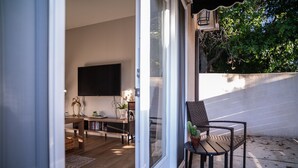 A modern living room with a flat-screen TV, wooden furniture, and a dining area.