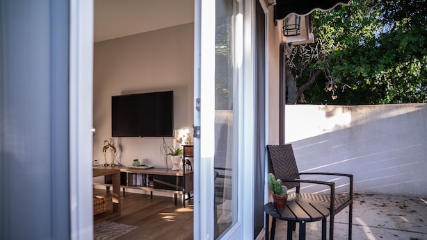 A modern living room with a flat-screen TV, wooden furniture, and a dining area.