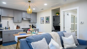 A modern kitchen with grey cabinets, a dining table, and a blue sofa with white cushions.