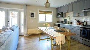 A modern kitchen with a dining table, a sofa, and a view of the outdoors.