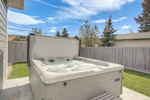 Un bain à remous installé à l’extérieur, avec une clôture en bois et des arbres en arrière-plan.