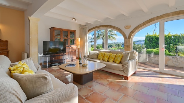 A spacious living room with a large TV, comfortable seating, and a view of the outdoors. - La Desirada - Javea, Costa Blanca (Javea)