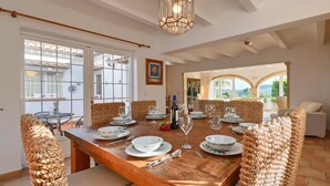 A dining area with a wooden table set for six, surrounded by woven chairs. - La Desirada - Javea, Costa Blanca (Javea)