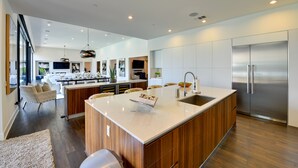 A modern kitchen with a large island, stainless steel appliances, and a view to the living area. - Mtn Views + Outdoor Oasis: Palm Springs Home! (Palm Springs)