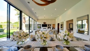 A spacious dining area with a long table set for a meal, large windows, and a modern interior design. - Mtn Views + Outdoor Oasis: Palm Springs Home! (Palm Springs)