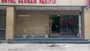 The exterior of Hotel Sangam Pacific with a large entrance and potted plants in front.