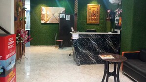 A hotel reception area with a marble counter, green walls, and a framed picture above the counter.