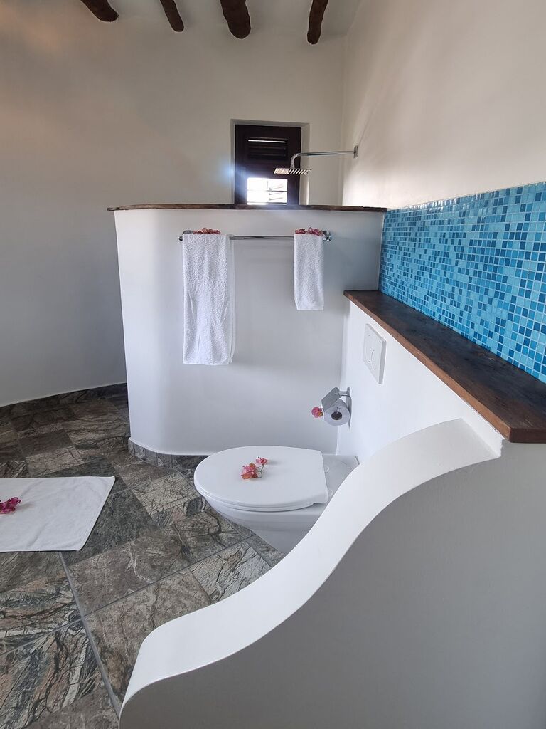 A bathroom with a toilet, a shower, and a sink.