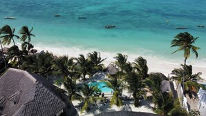 Ein Strandresort mit Pool, Palmen und Booten auf dem Wasser.