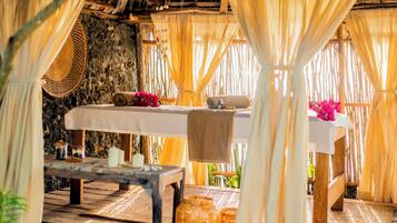 Un comedor rústico con pared de piedra, mobiliario de madera y techo de paja.