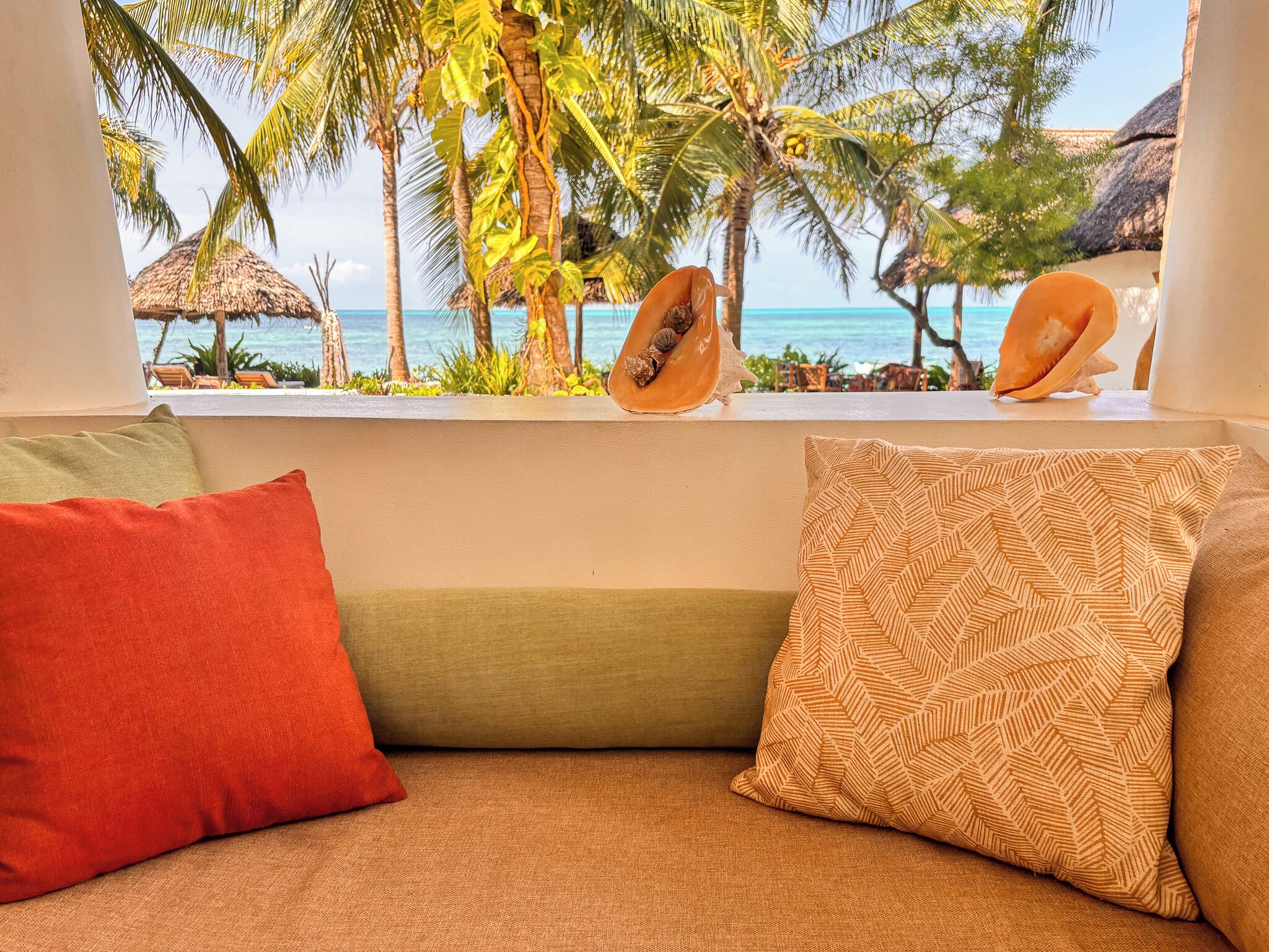 A view from a window with a beach and palm trees.