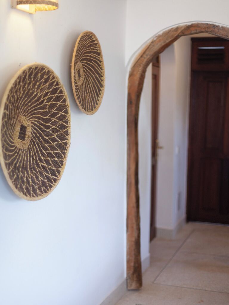 A hallway with a wooden archway and two wall-mounted decorative items.