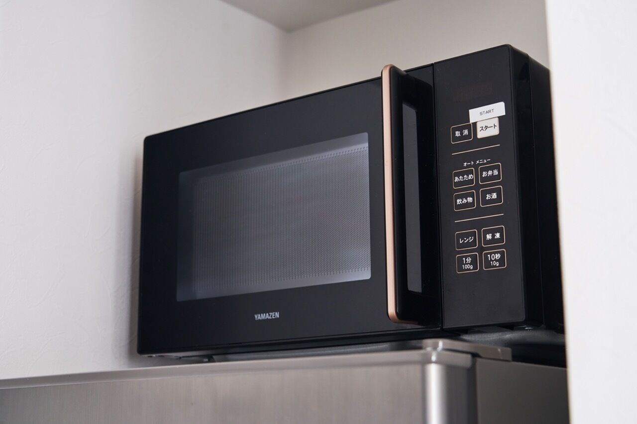 A black microwave oven with a digital control panel, mounted on a kitchen counter.